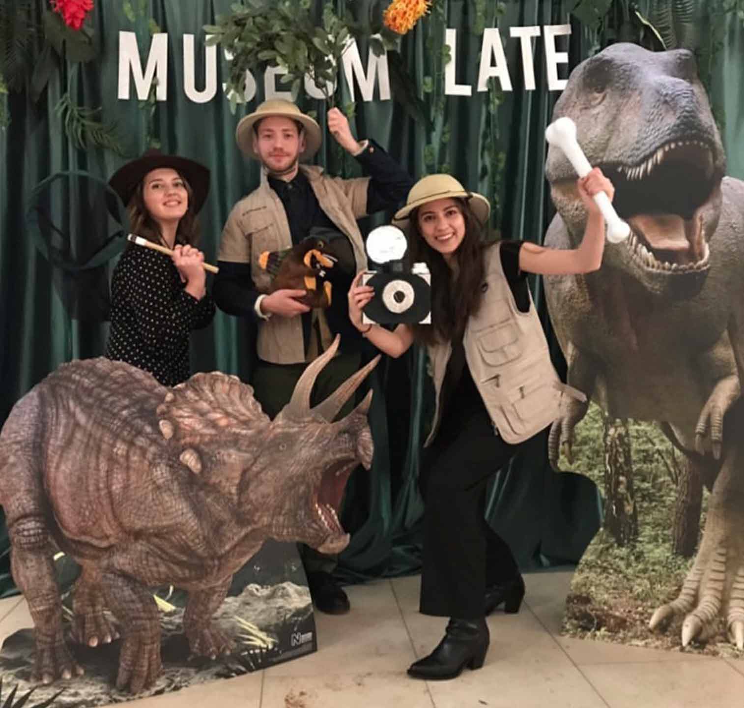 The Media Shop team - in front of a museum backdrop, striking a pose beside cardboard dinosaurs